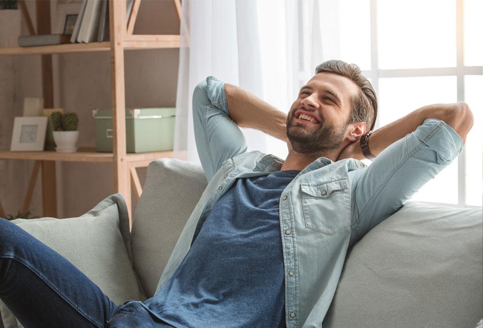 Mann sitzt lachend auf dem Sofa