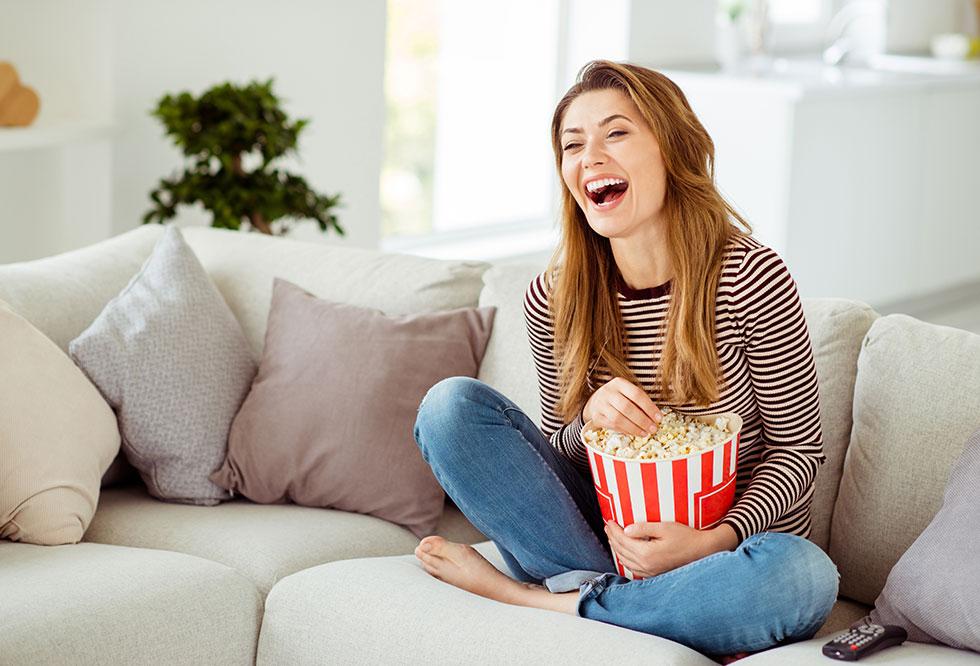 Frau sitzt auf Couch mit Popcorn 